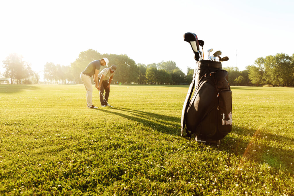 senior male coach teaching young sportsman how play golf x